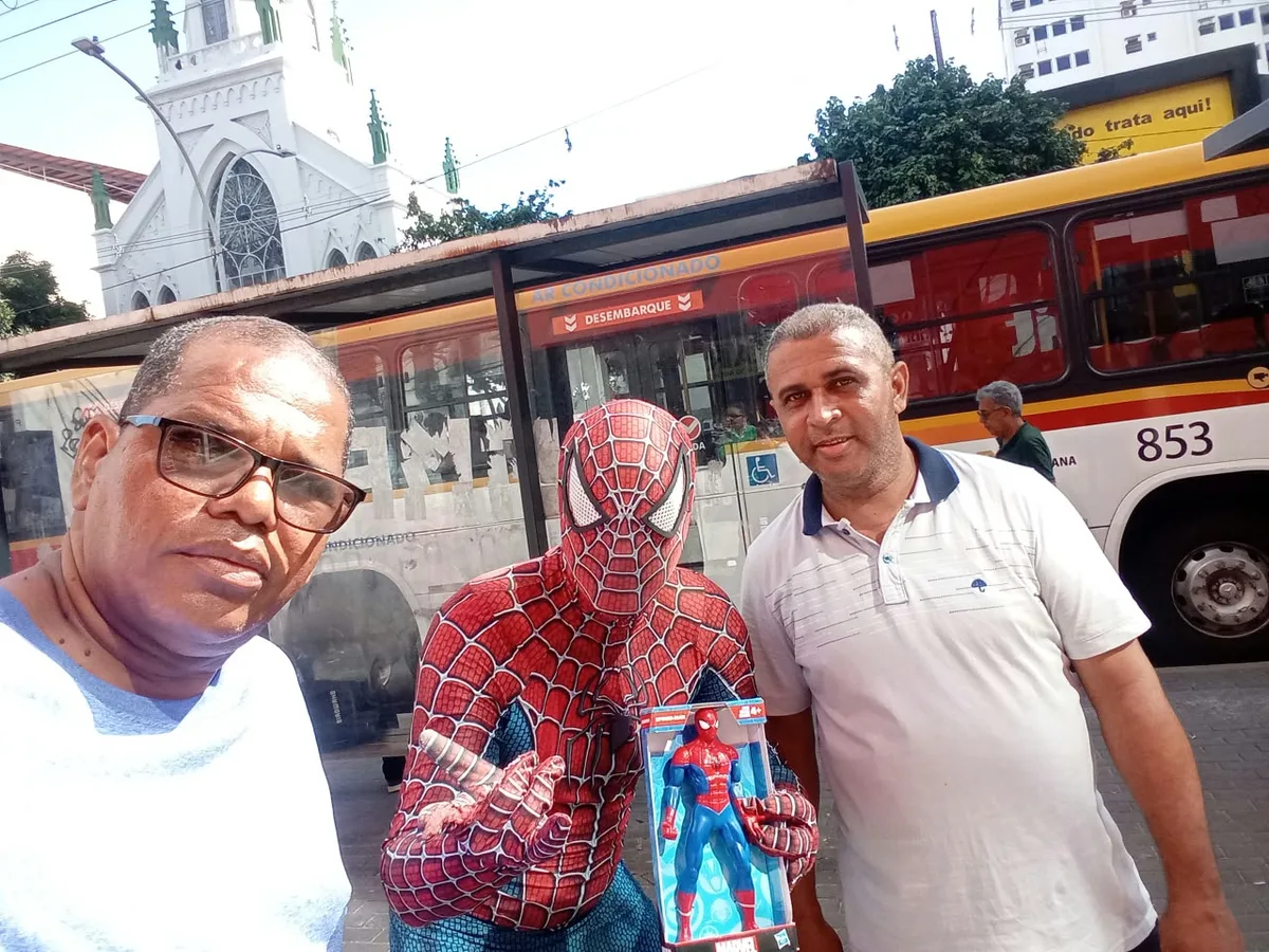 Homem-Aranha com um boneco na rua, no Dia das Crianças